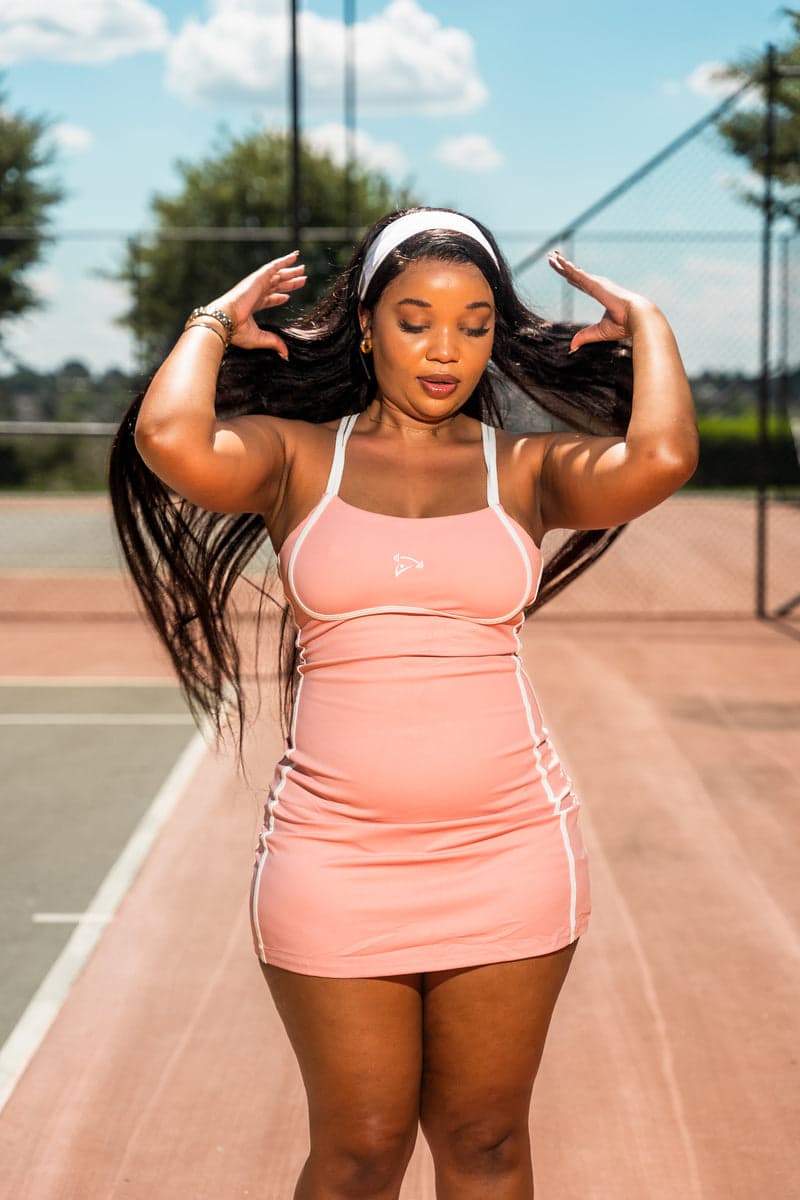 A woman wearing the Pink Active Dress on the tennis court